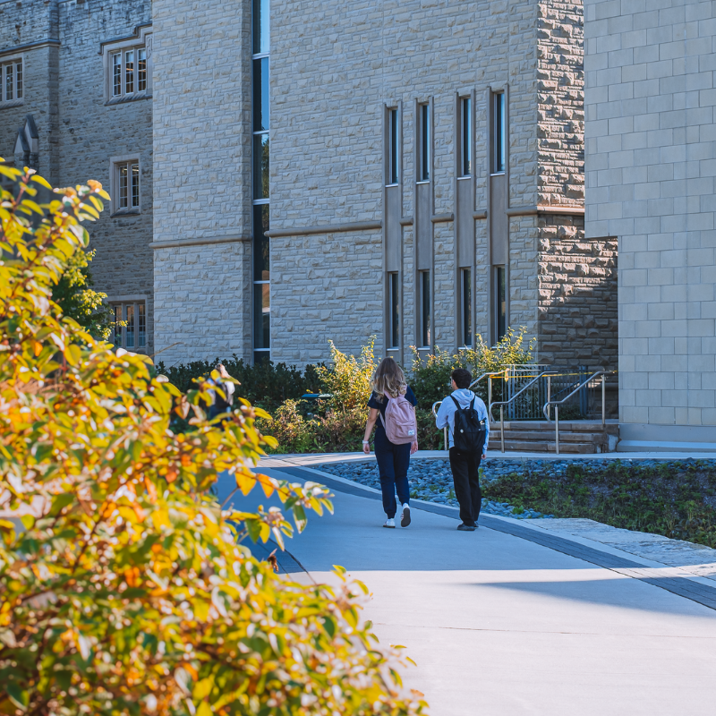 A pair of students walking on Western's campus beside the Don Wright Faculty of Music Building
