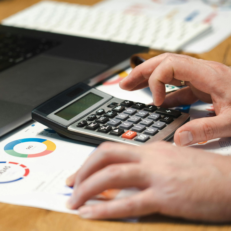 Student using a calculator with charts and graphs in the background