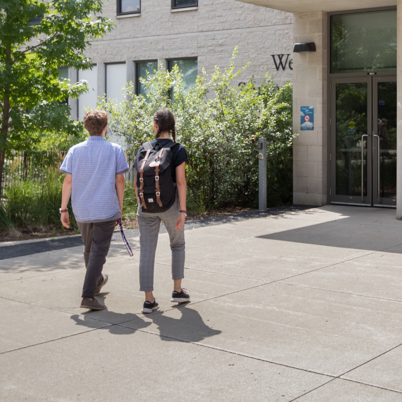 Two students walking towards the enterance of the Western Student Services Building