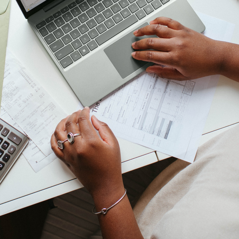 A photo of someone's hands at a computer working on budgeting and finances