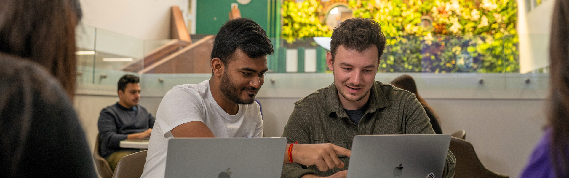 Two people working together on laptops in a modern indoor study space