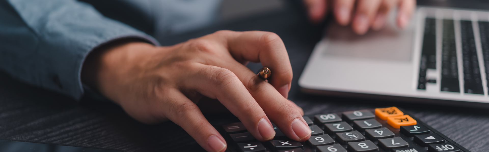 Student using a calculator and laptop to manage finances