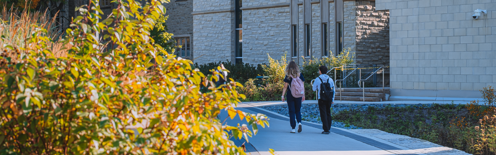 A pair of students walking on Western's campus beside the Don Wright Faculty of Music Building