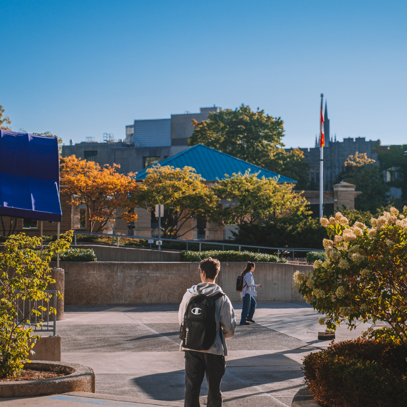 A student wearing a backpack walking on concrete beach on a sunny day