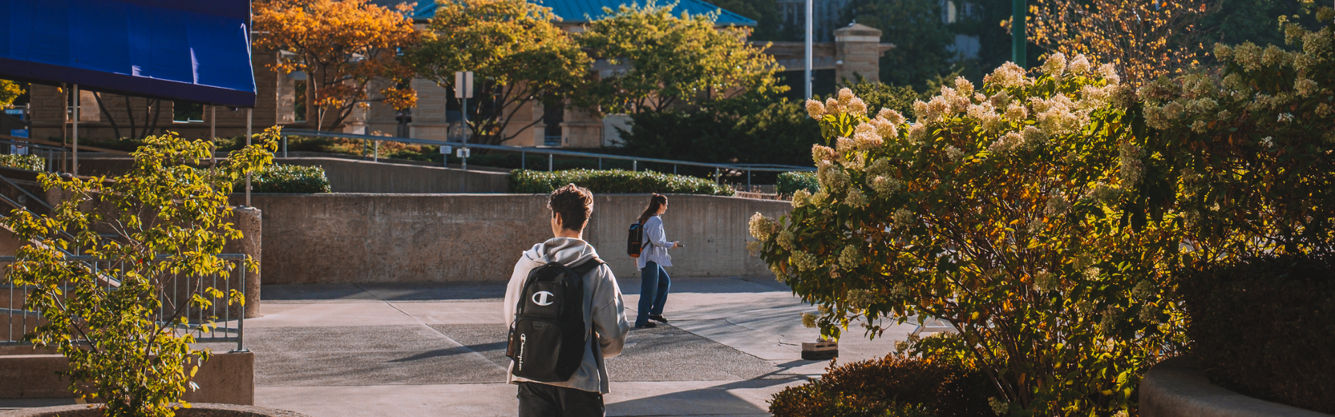 A student wearing a backpack walking on concrete beach on a sunny day