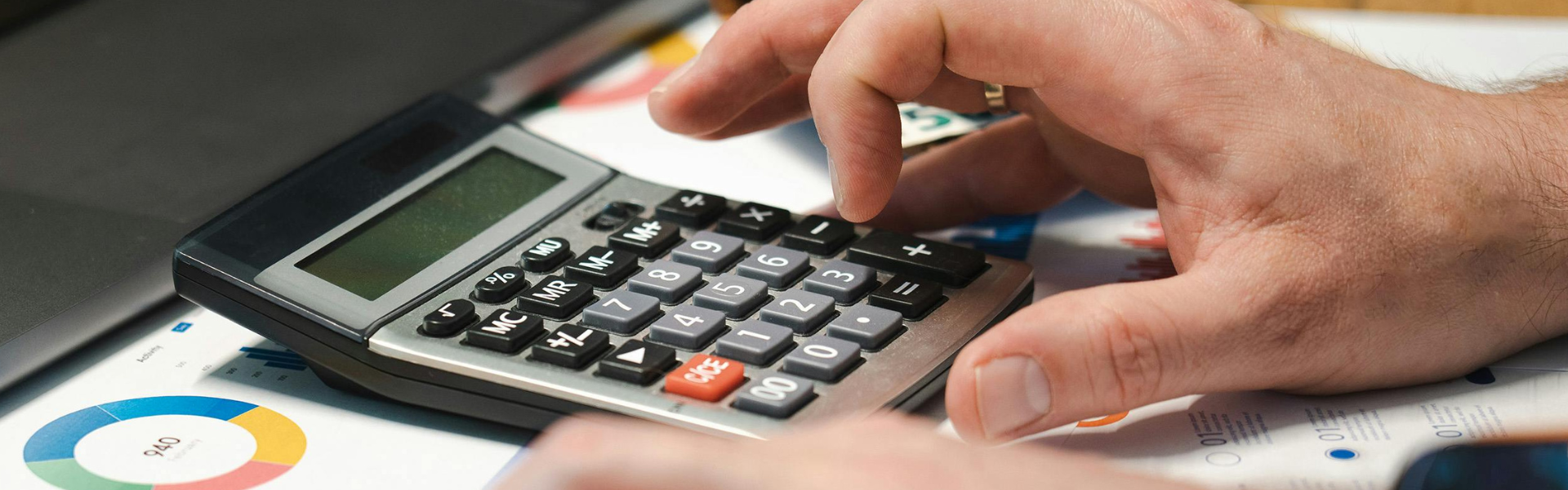 Student using a calculator with charts and graphs in the background