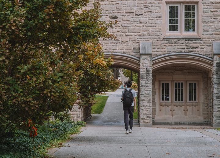 A student wearing a backpack walking on campus 