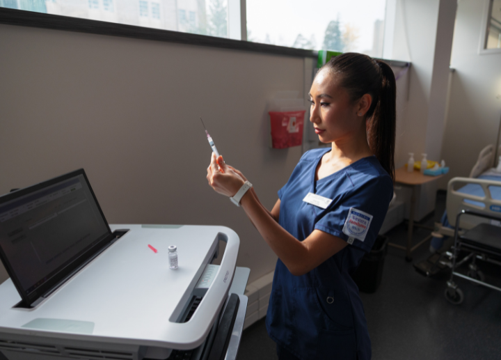 A student wearing scrubs holding a needle