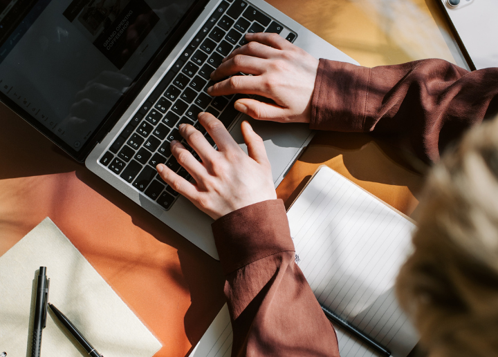Hands typing on a laptop