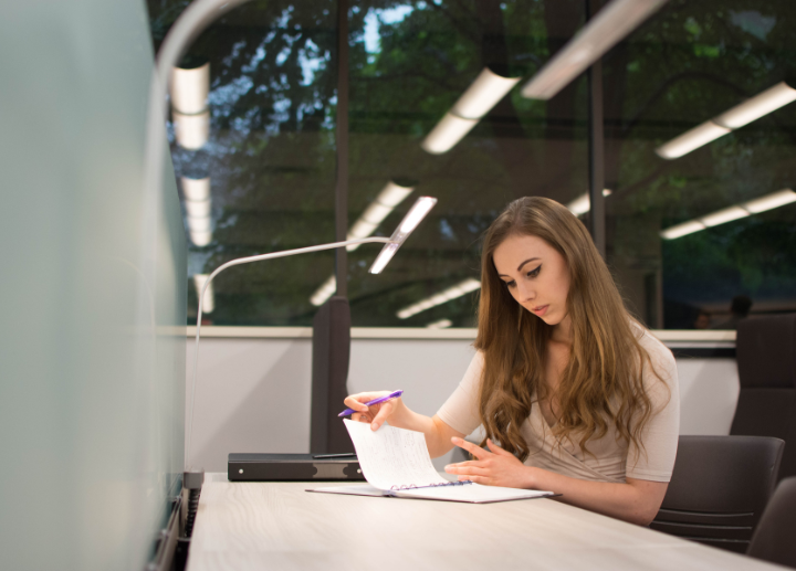 A student sitting at a desk reviewing paperwork in a binder